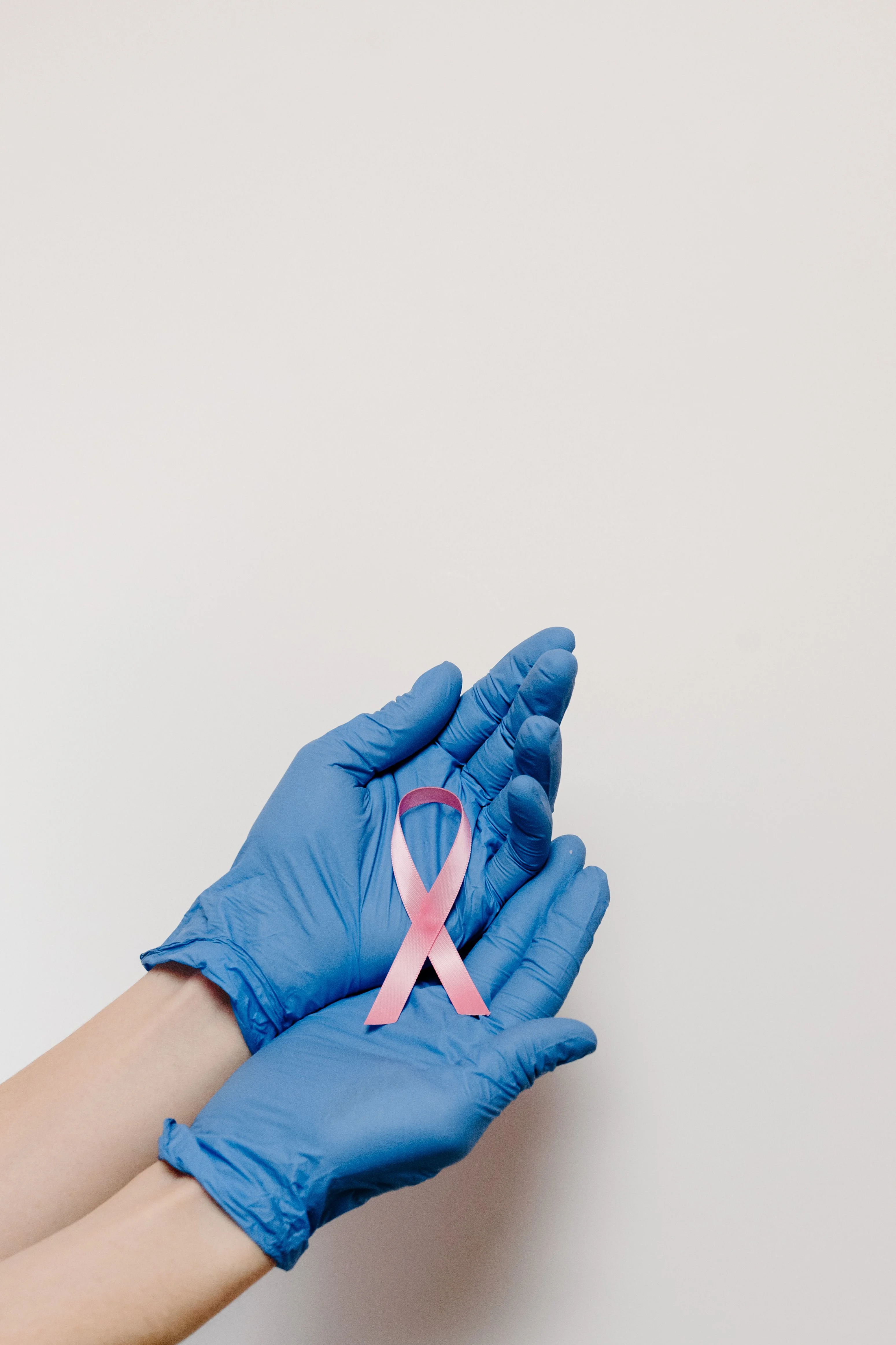 Hands holding a pink cancer awareness ribbon, symbolising supportive oncology care
